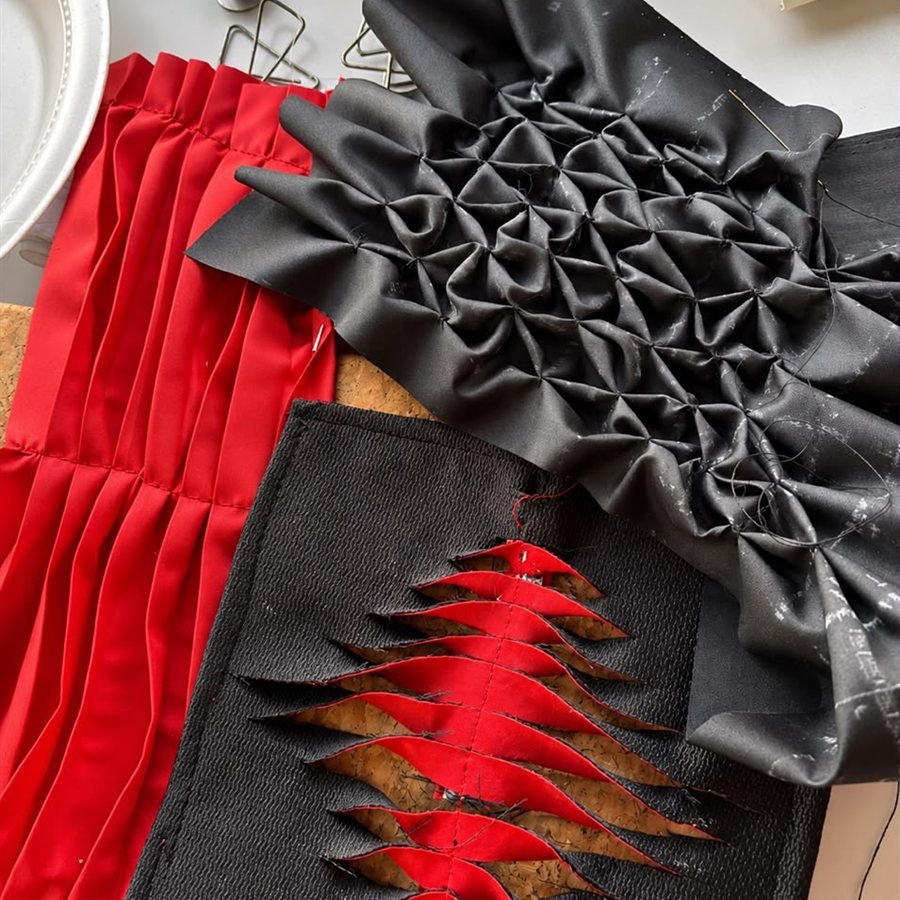 Muestras de técnicas textiles: smocking negro, plisado rojo y cortes en capas rojo y negro