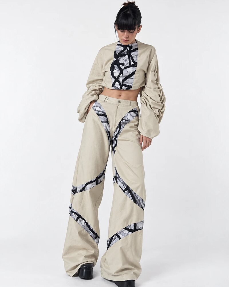 Modelo con conjunto beige de mangas abullonadas y pantalón ancho con franjas de textura